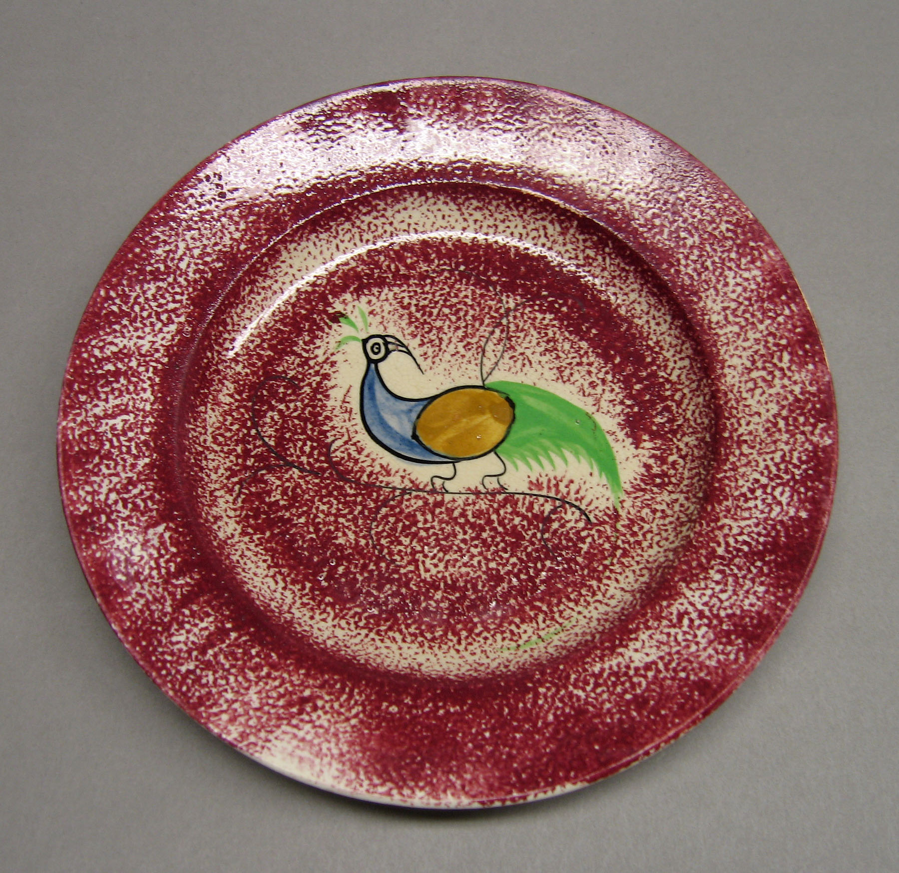 1965.0879 Pink spatter plate with peafowl pattern
