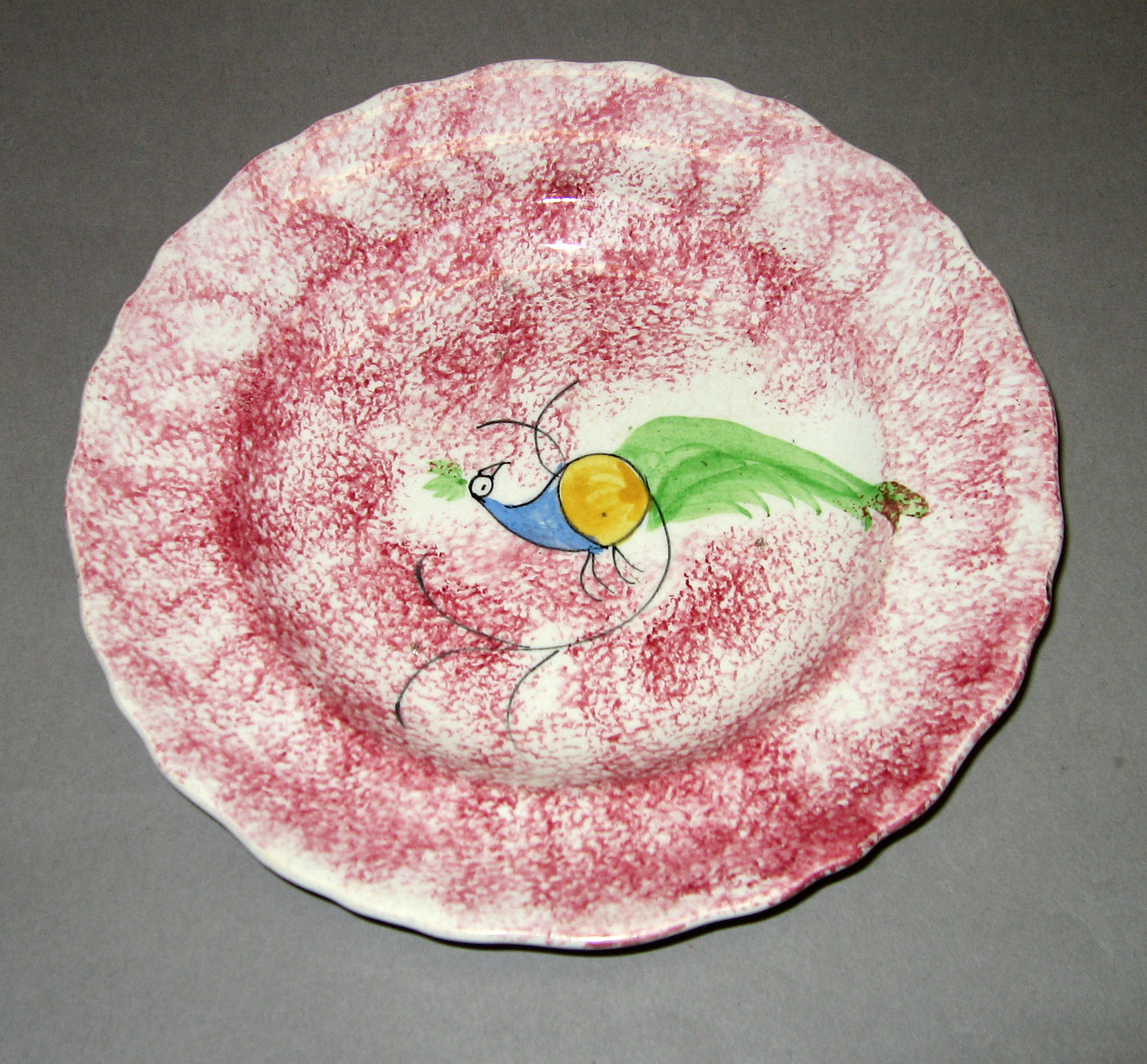 1965.0881.006 Pink spatter plate with peafowl pattern