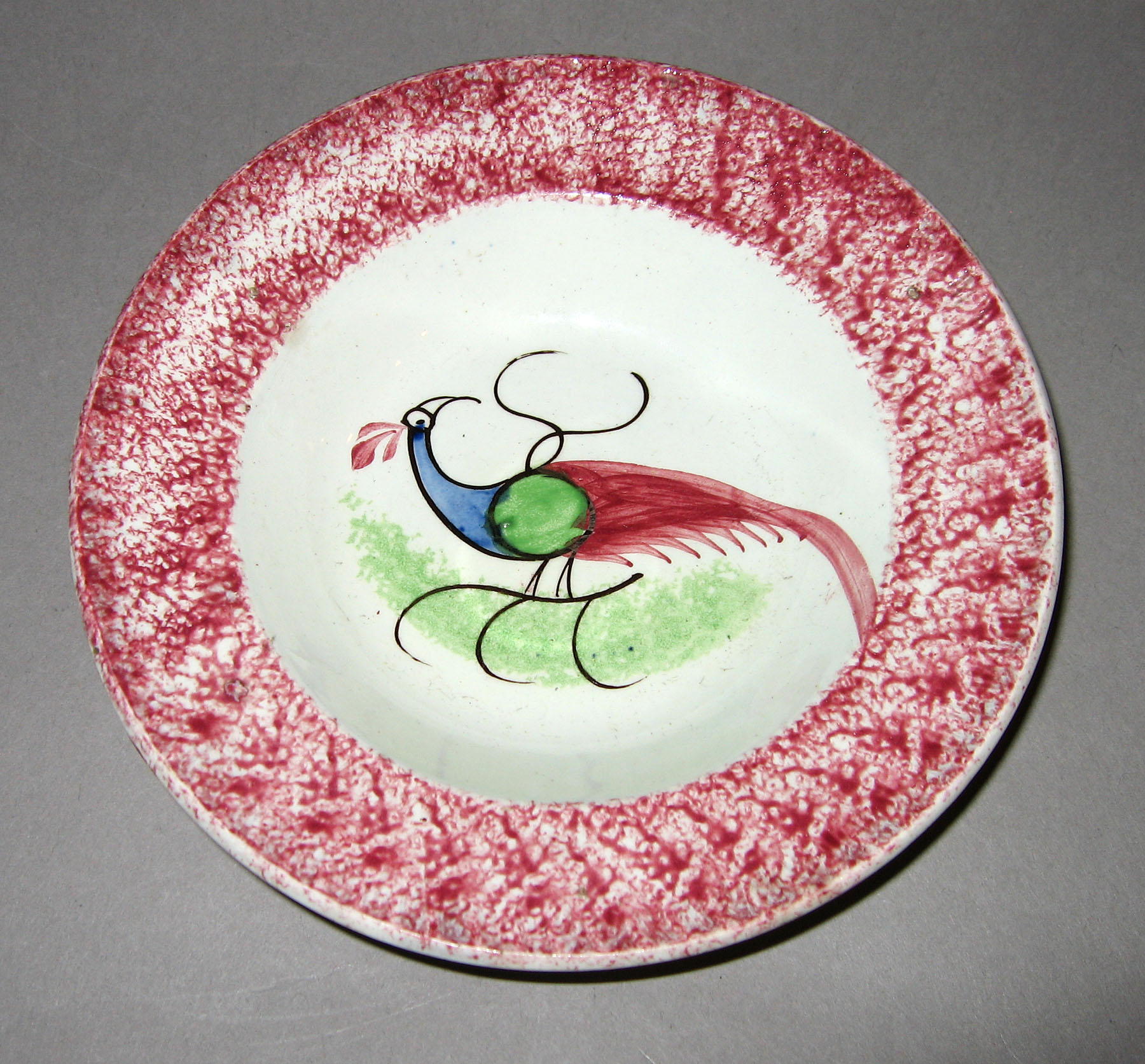 1965.0896.007 Pink spatterware peafowl saucer