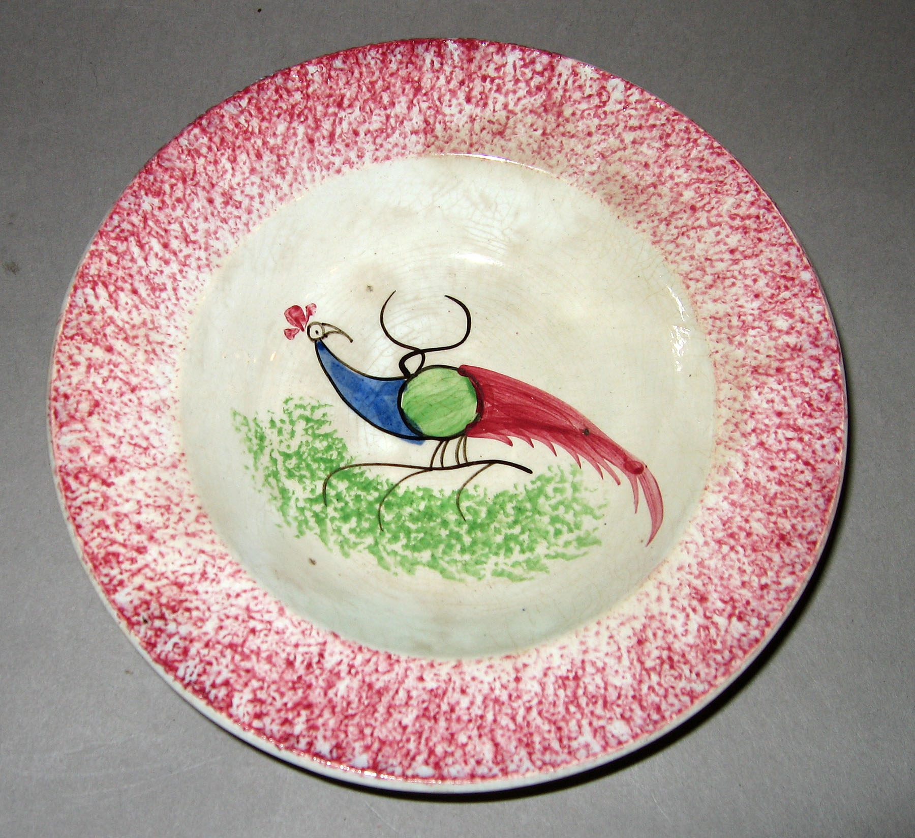 1965.0896.008 Pink spatterware peafowl saucer