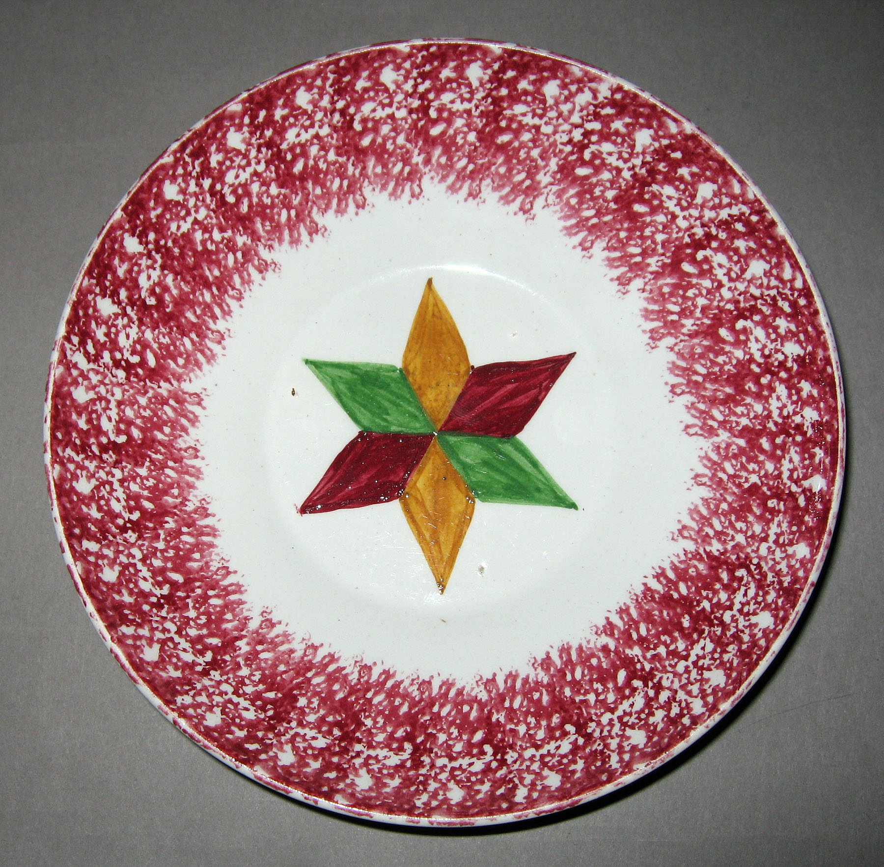 1965.0904 Pink spatterware and tri-color star pattern saucer