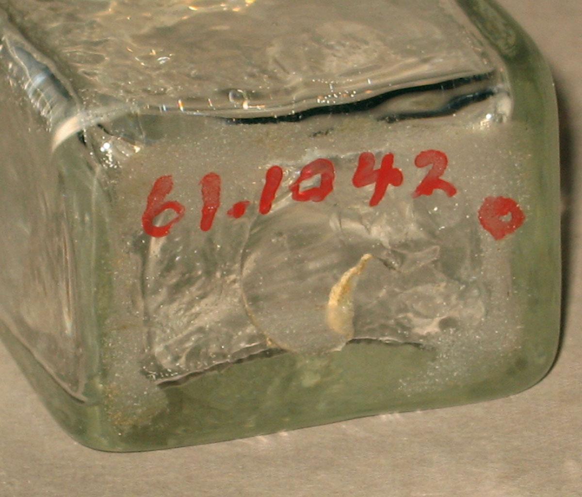 1961.1042 O Glass bottle (underside)