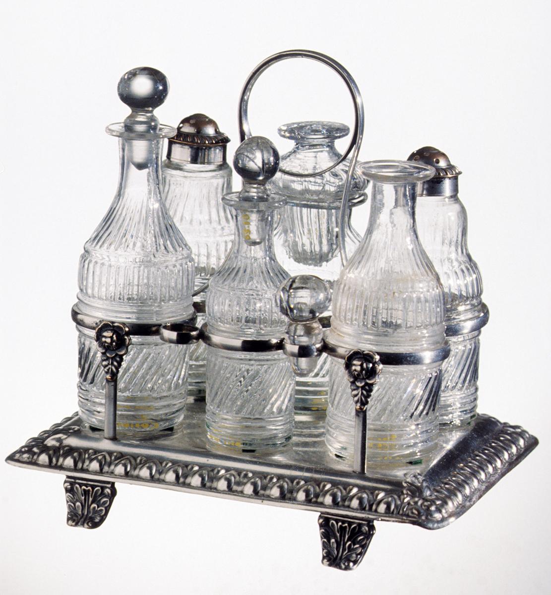 1983.0010 A- M Silver stand with glass cruet bottles and castors